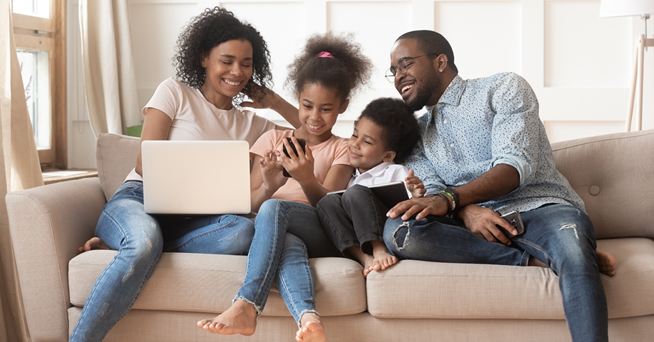 Parents and kids sitting on couch around a computer.